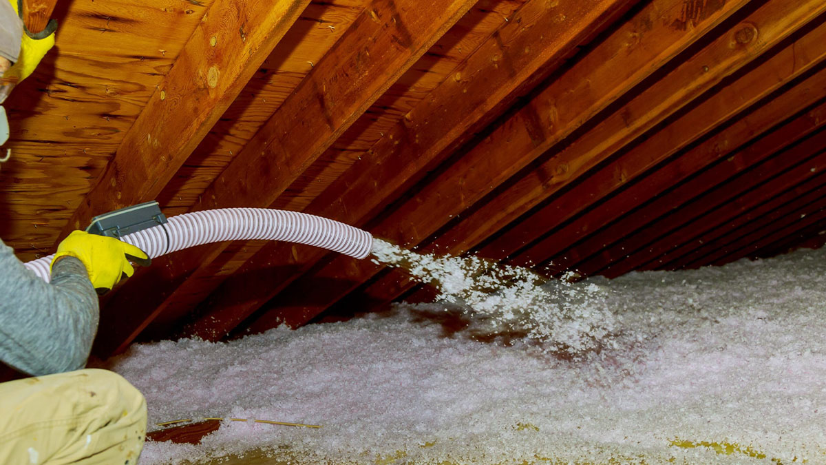 technician spraying blown fiberglass insulation 